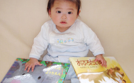 絵本に手を置く生後6か月の赤ちゃん